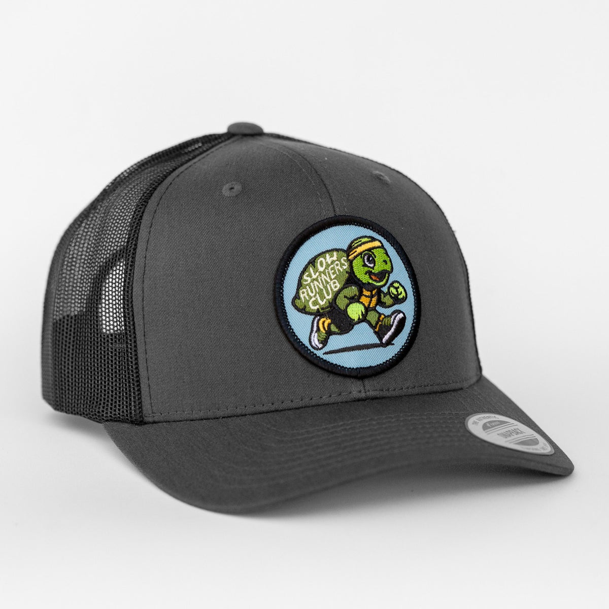 Angled to one side, the charcoal Slow Runners Club trucker hat pairs black mesh with its running turtle patch.