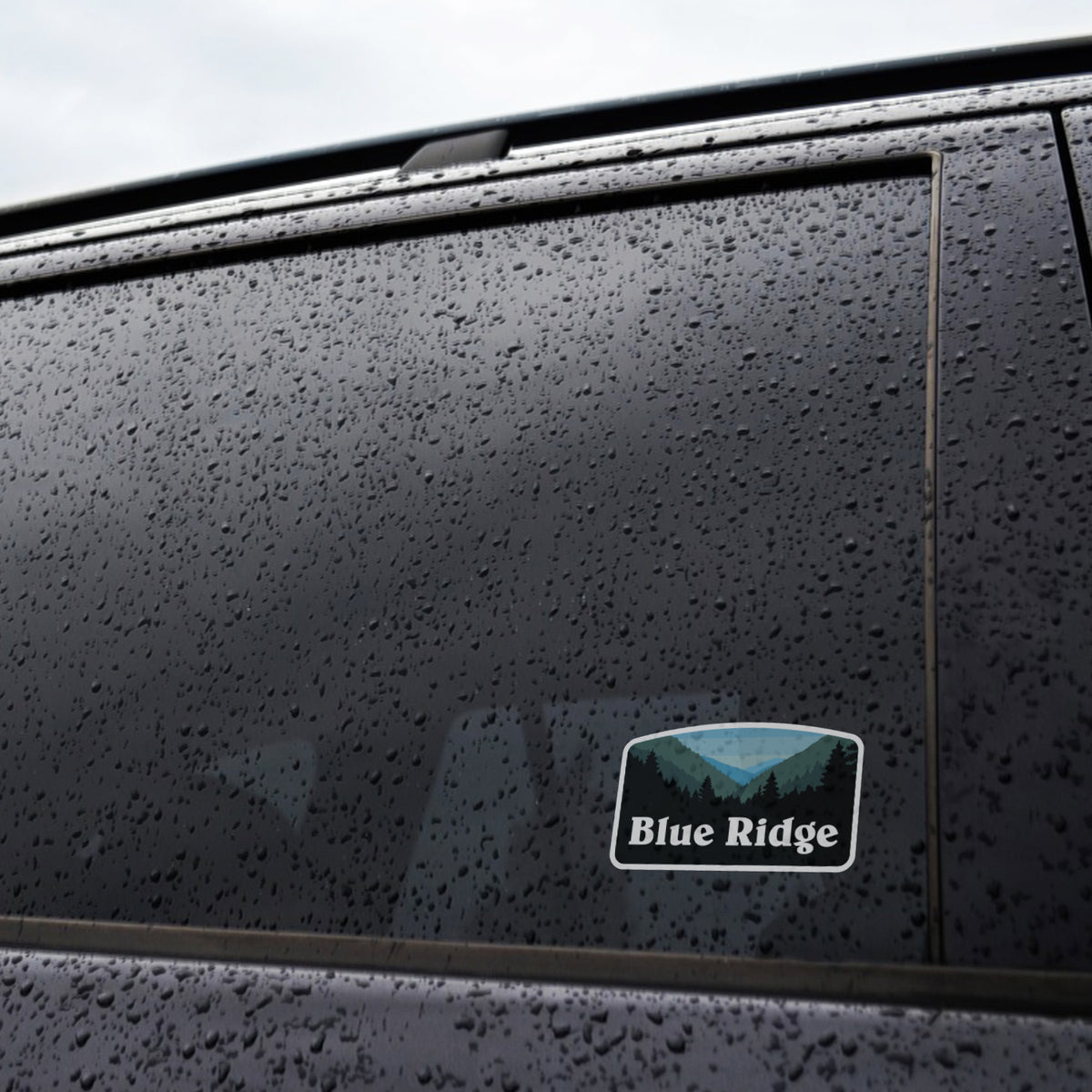 A rain streaked car window shows the Blue Ridge sticker fixed near the lower corner of the glass.