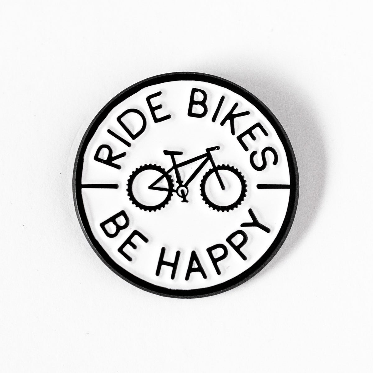 A round black and white Ride Bikes Be Happy pin sits on a plain white background, its bicycle icon centered.