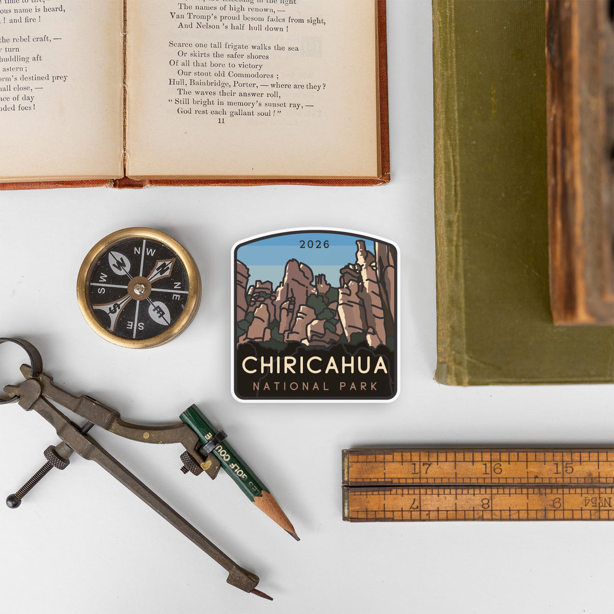 Beside a compass, ruler, and antique book, the Chiricahua National Park sticker sits among tools for old fashioned mapmaking.