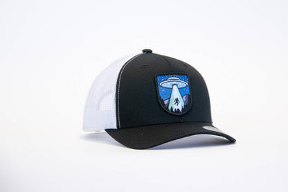 Black crown with white mesh sides on the Bigfoot UFO Conspiracy trucker hat, saucer patch centered on the front.