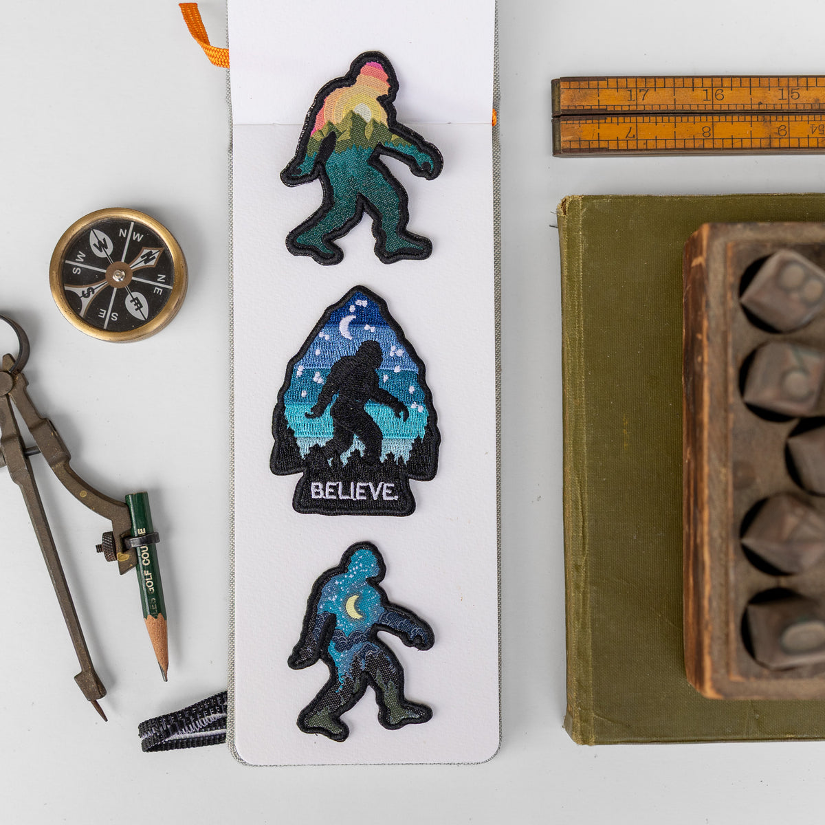 A display card holds three Bigfoot patches, the bottom one a starry night sky version beside a mountain and arrowhead design.
