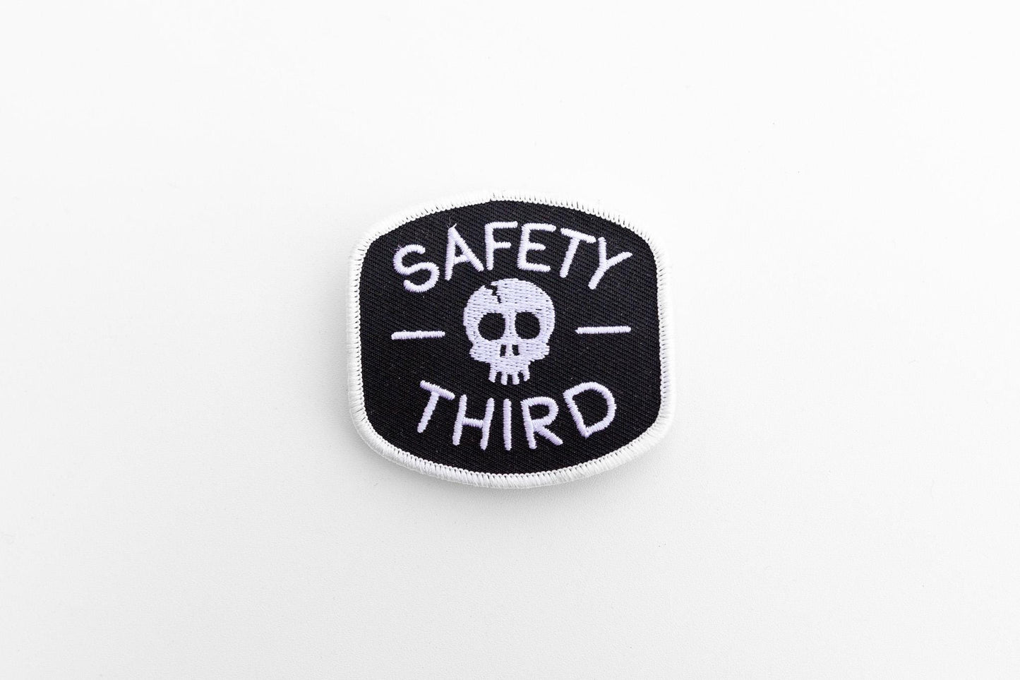Centered on a plain white background, the small Safety Third patch shows its skull between two dashes.