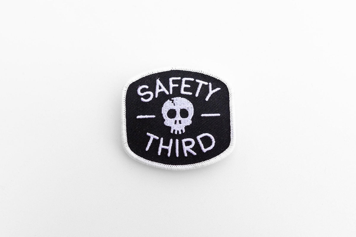 Centered on a plain white background, the small Safety Third patch shows its skull between two dashes.