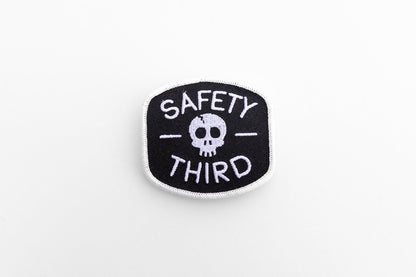 Centered on a plain white background, the small Safety Third patch shows its skull between two dashes.