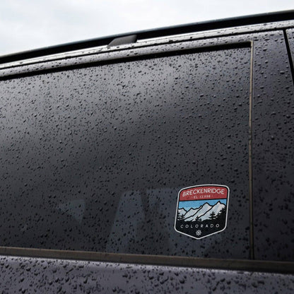 Rain beads across a dark car window where the small Breckenridge Colorado sticker sits near the corner.
