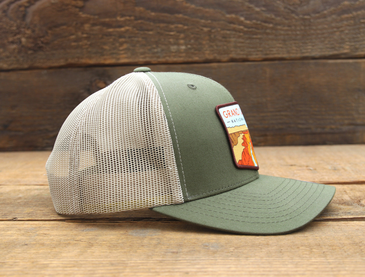 Side profile on weathered planks, the Grand Canyon trucker hat shows its patch edge and stitched brim.