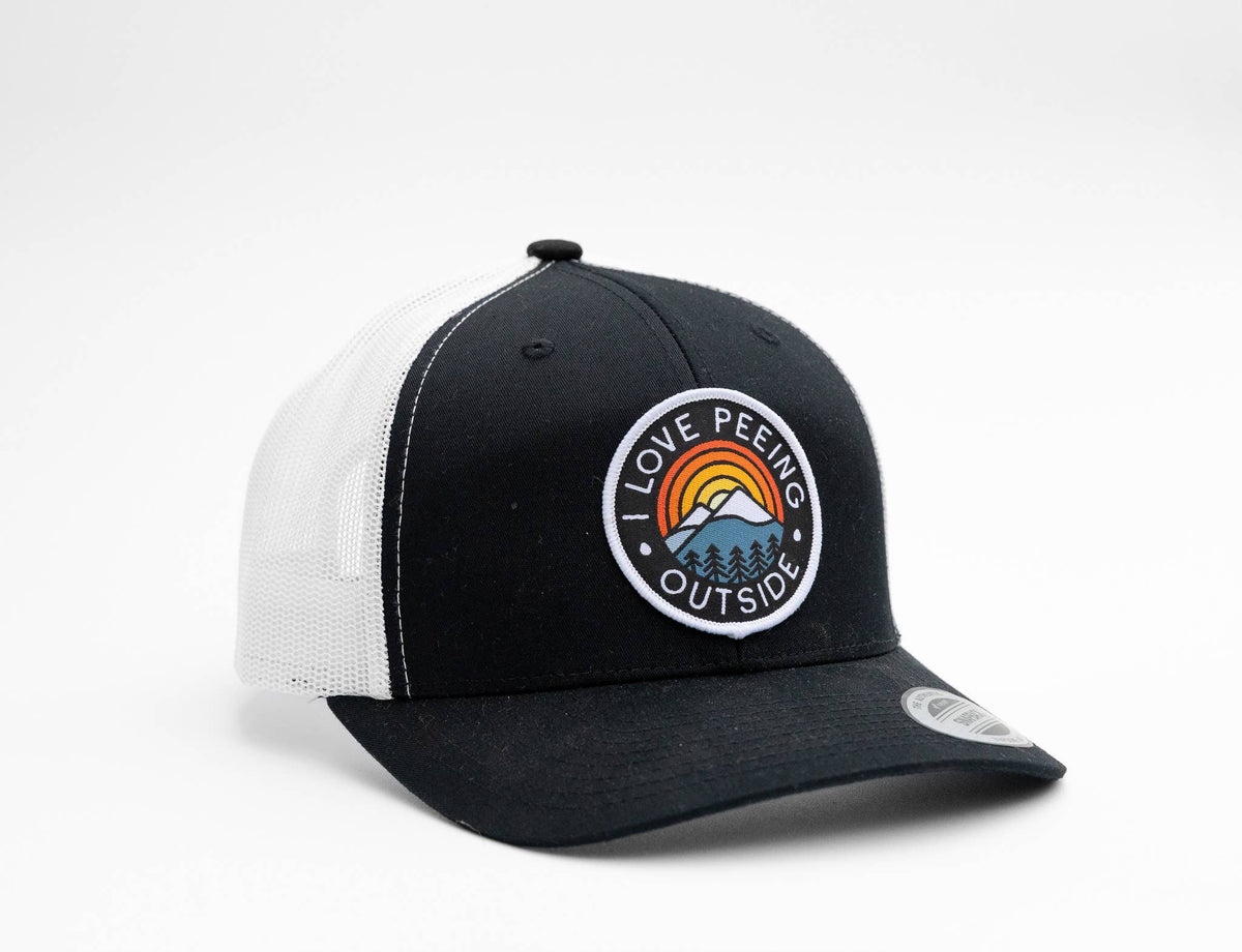 Black and white I Love Peeing Outside trucker hat turned so the patch catches the light.