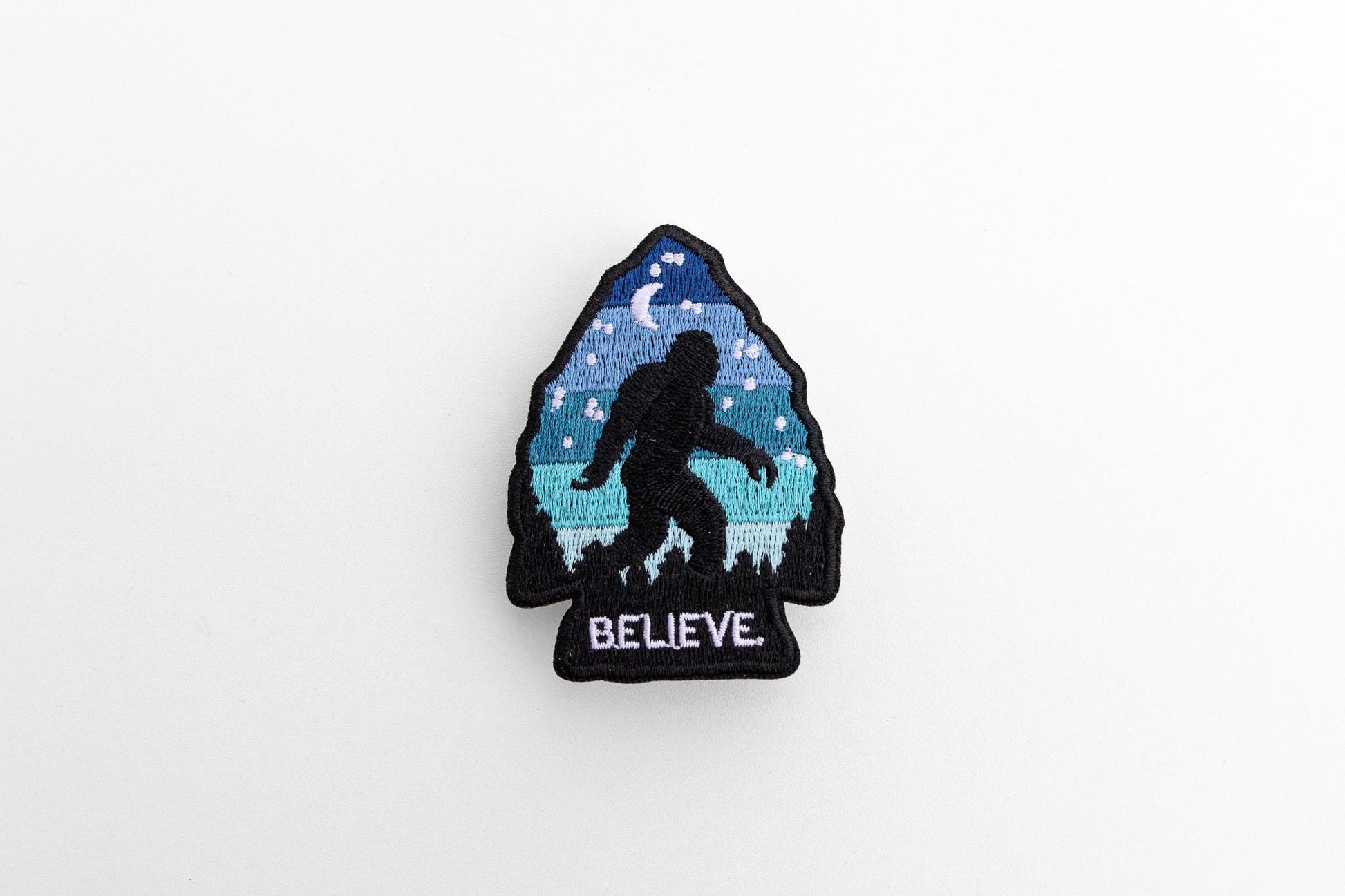 Centered on a pale grey background, the Bigfoot Believe patch shows its black merrowed border.