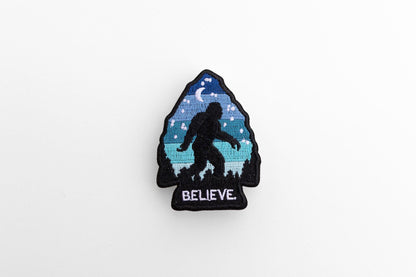 Centered on a pale grey background, the Bigfoot Believe patch shows its black merrowed border.