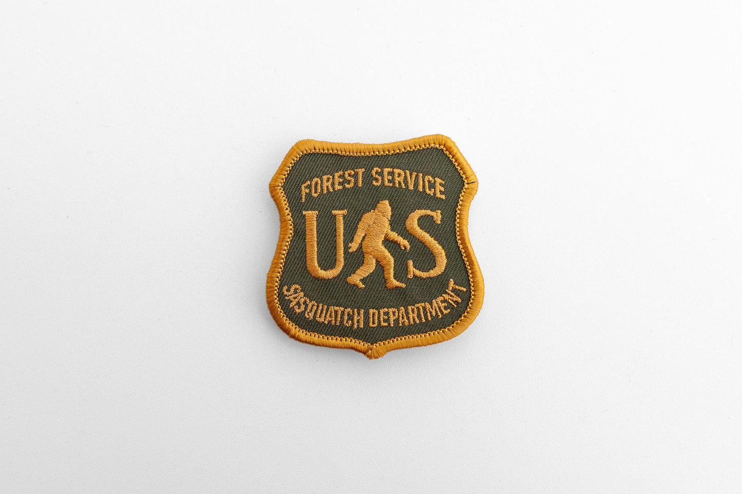 Small against a plain pale backdrop, the US Sasquatch Department patch reads Forest Service across the top.