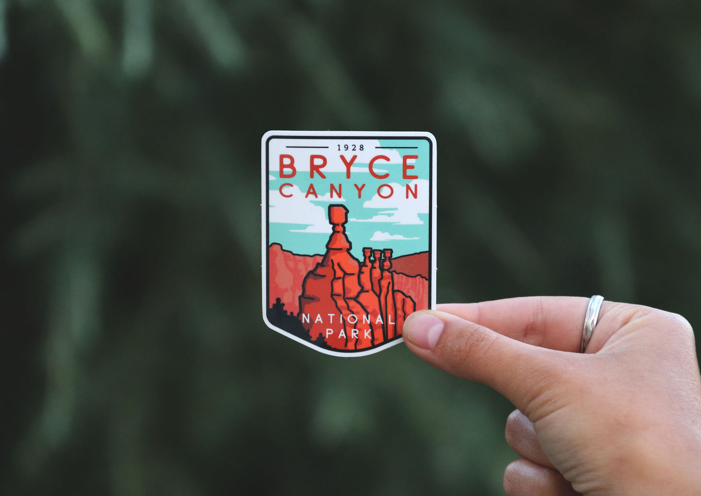 Wider framing puts the Bryce Canyon National Park sticker off to the right, hoodoos facing a soft evergreen backdrop.