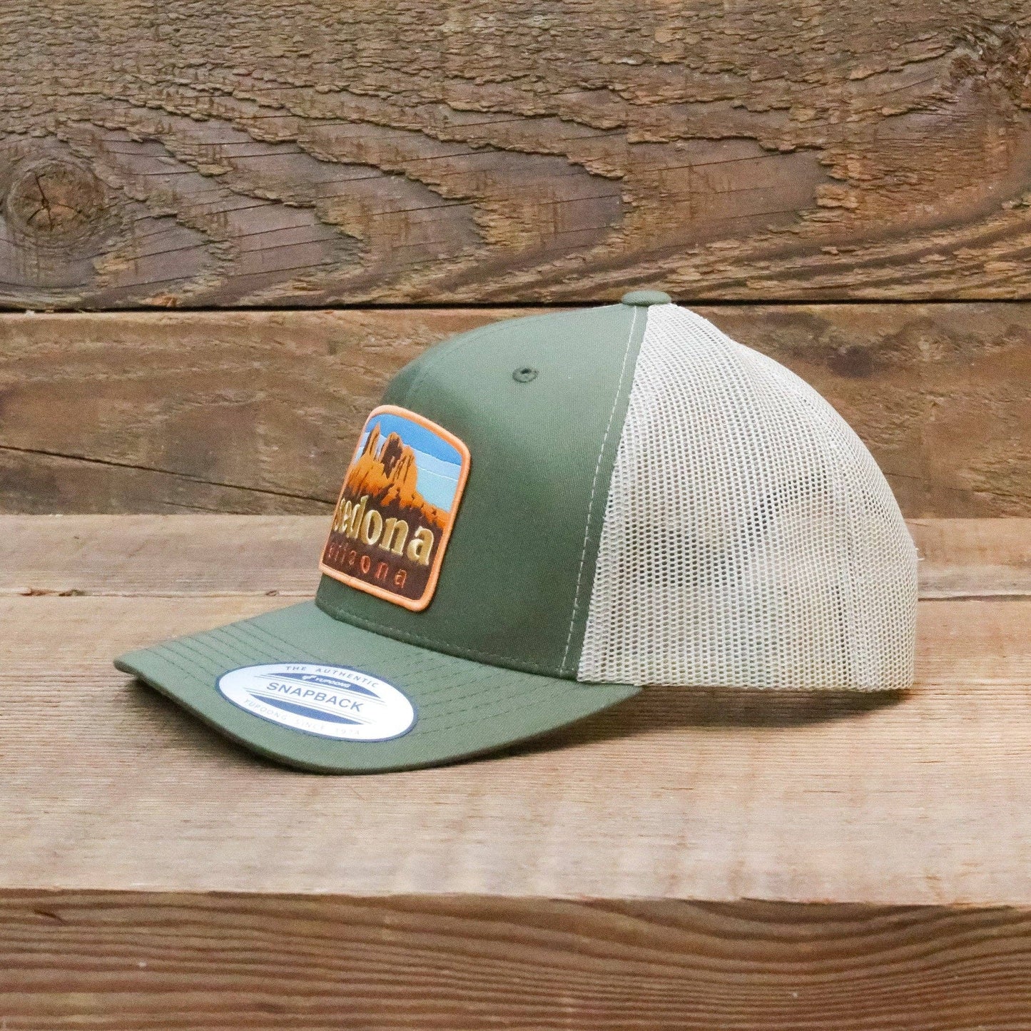Propped on weathered barn wood, the green Sedona Arizona trucker hat still wears its snapback brim label.