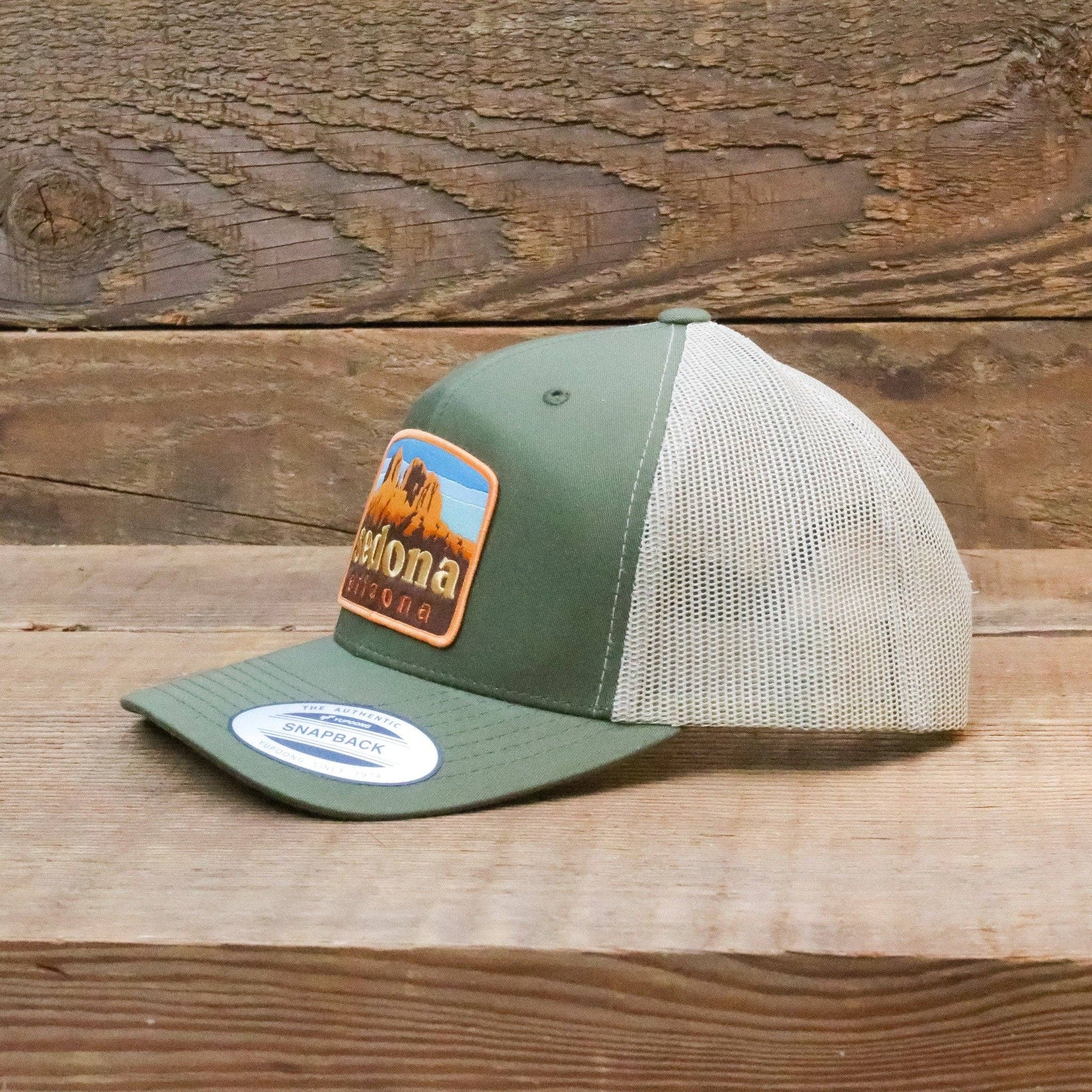 Propped on weathered barn wood, the green Sedona Arizona trucker hat still wears its snapback brim label.