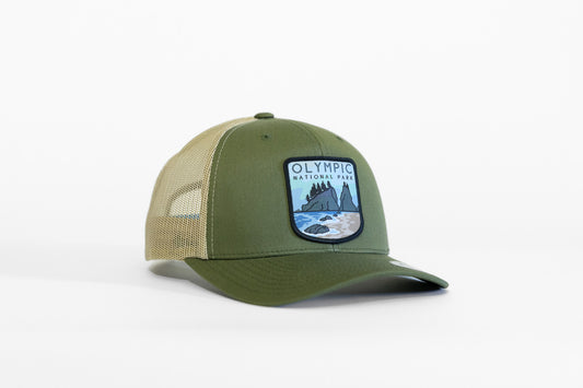 Angled on a white background, the olive and tan Olympic National Park trucker hat shows its sea stack patch.