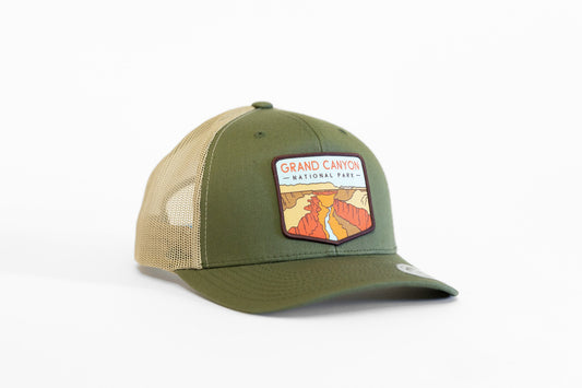 Angled on white, the olive Grand Canyon National Park trucker hat shows its canyon patch and tan mesh back.