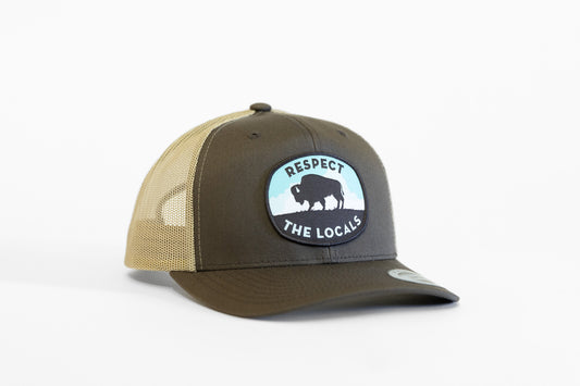 Angled on white, the brown Respect The Locals Bison Trucker Hat pairs a tan mesh back with its oval patch.