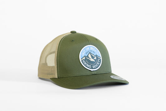 Olive and khaki Out of Breath Hiking Society trucker hat angled to show its round blue mountain patch.