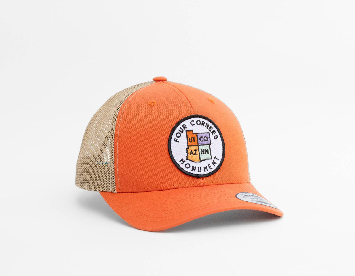 Orange twill and khaki mesh meet on the Four Corners Monument trucker hat resting against a plain backdrop.