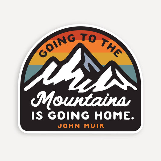 Arched Going to the Mountains is Going Home sticker with white peaks and sunset stripes on a pale background.