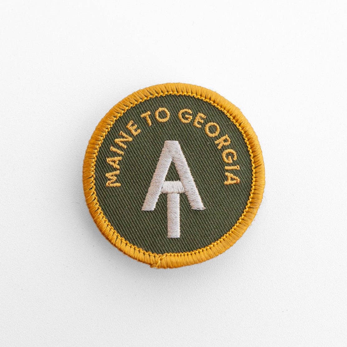 Green and gold AT Maine to Georgia patch lies flat on white, its yellow merrow edge circling the trail logo.