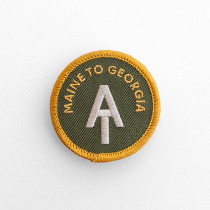 Green and gold AT Maine to Georgia patch lies flat on white, its yellow merrow edge circling the trail logo.