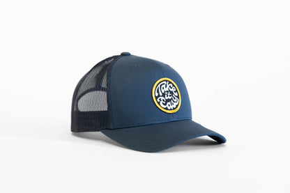 Navy Take it Easy trucker hat turned three quarters, yellow ringed patch bright against the blue crown.