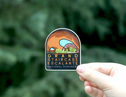 Pulled back a little, the same Grand Staircase Escalante sticker sits smaller in the frame over dark foliage.