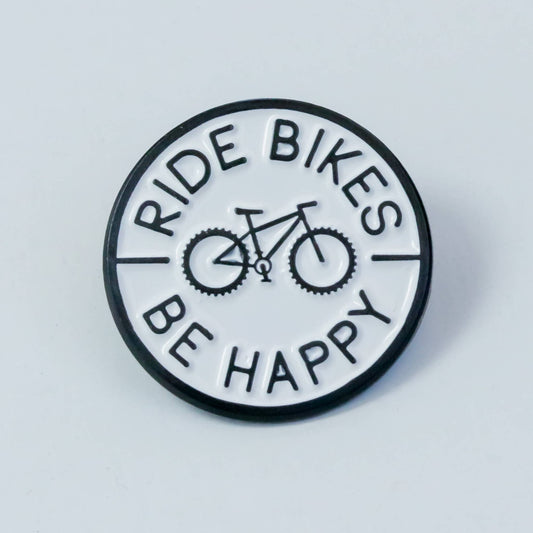 Round black and white Ride Bikes Be Happy enamel pin on a pale grey background, bicycle centered in the circle.