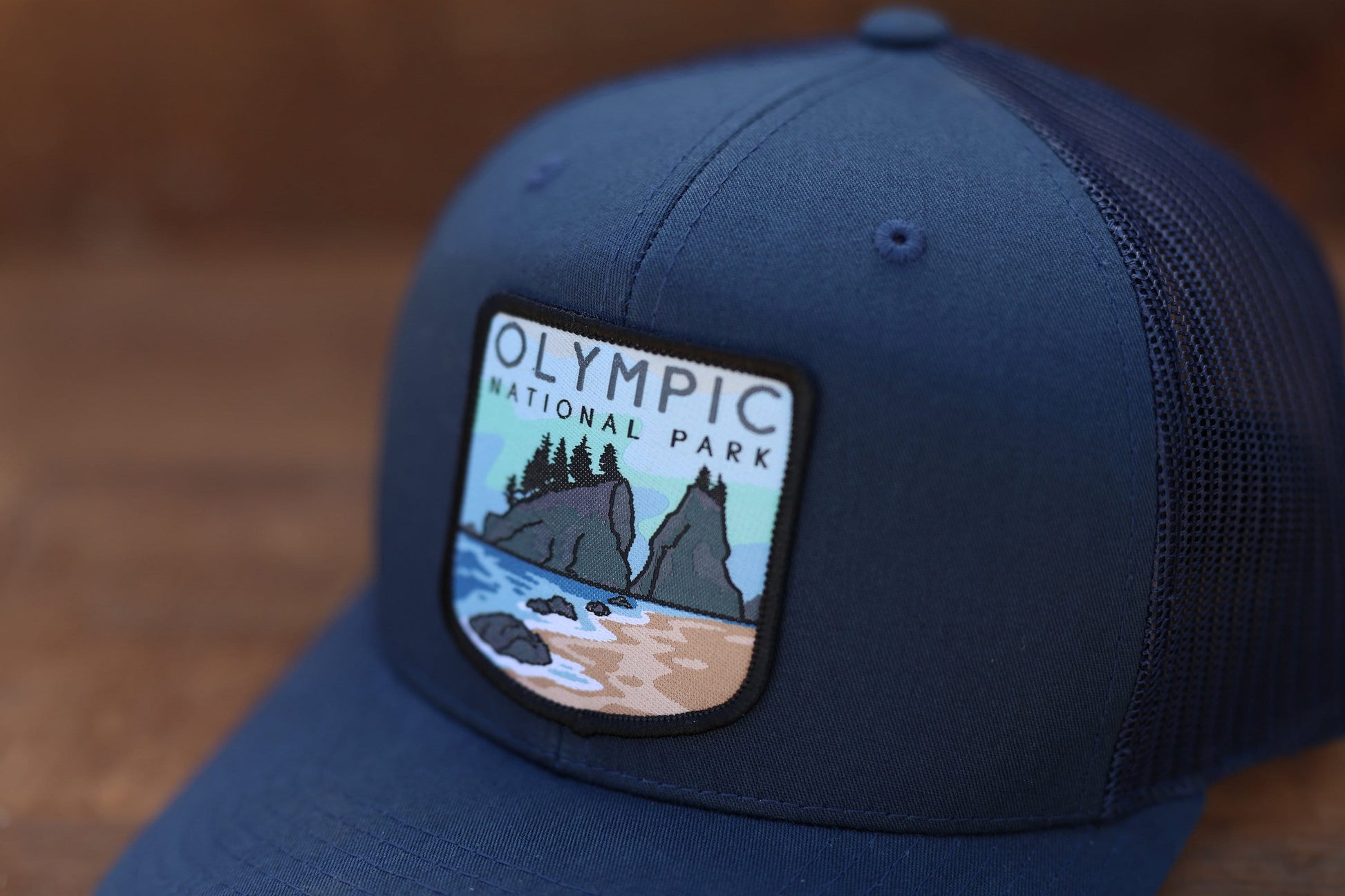 Tight crop across the navy crown, where the Olympic National Park patch shows rocks, beach and evergreens.