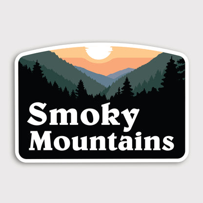 Against a plain grey background, the Smoky Mountains sticker shows a sunset over silhouetted ridgelines and pine trees.