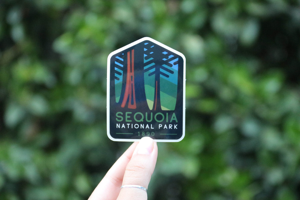 Farther back against the same blurred hedge, the Sequoia National Park sticker shows its 1890 date and arch shape.