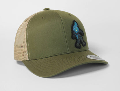 Turned to a three quarter angle, the olive Bigfoot Night Sky trucker hat shows the patch riding along the right panel.