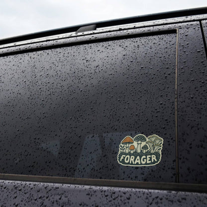Applied to a rain covered car window, the Forager Mushrooms sticker sits below beaded water drops.
