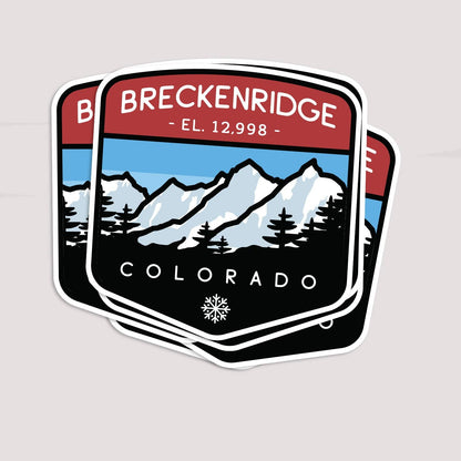 Three Breckenridge Colorado stickers fan out in a stack on a plain off white surface.