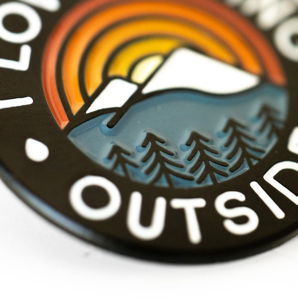 A close angle on the I Love Peeing Outside Pin catches the enameled sunset, mountain, and pine trees in raised detail.