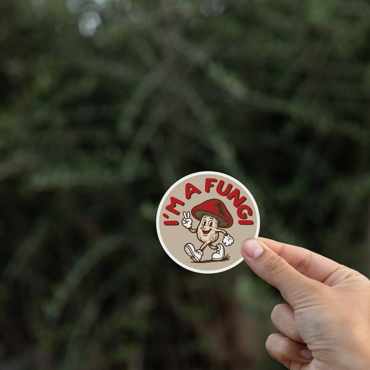 Pinched at the edge, the I'm a Fungi sticker sits small against a dark evergreen backdrop.