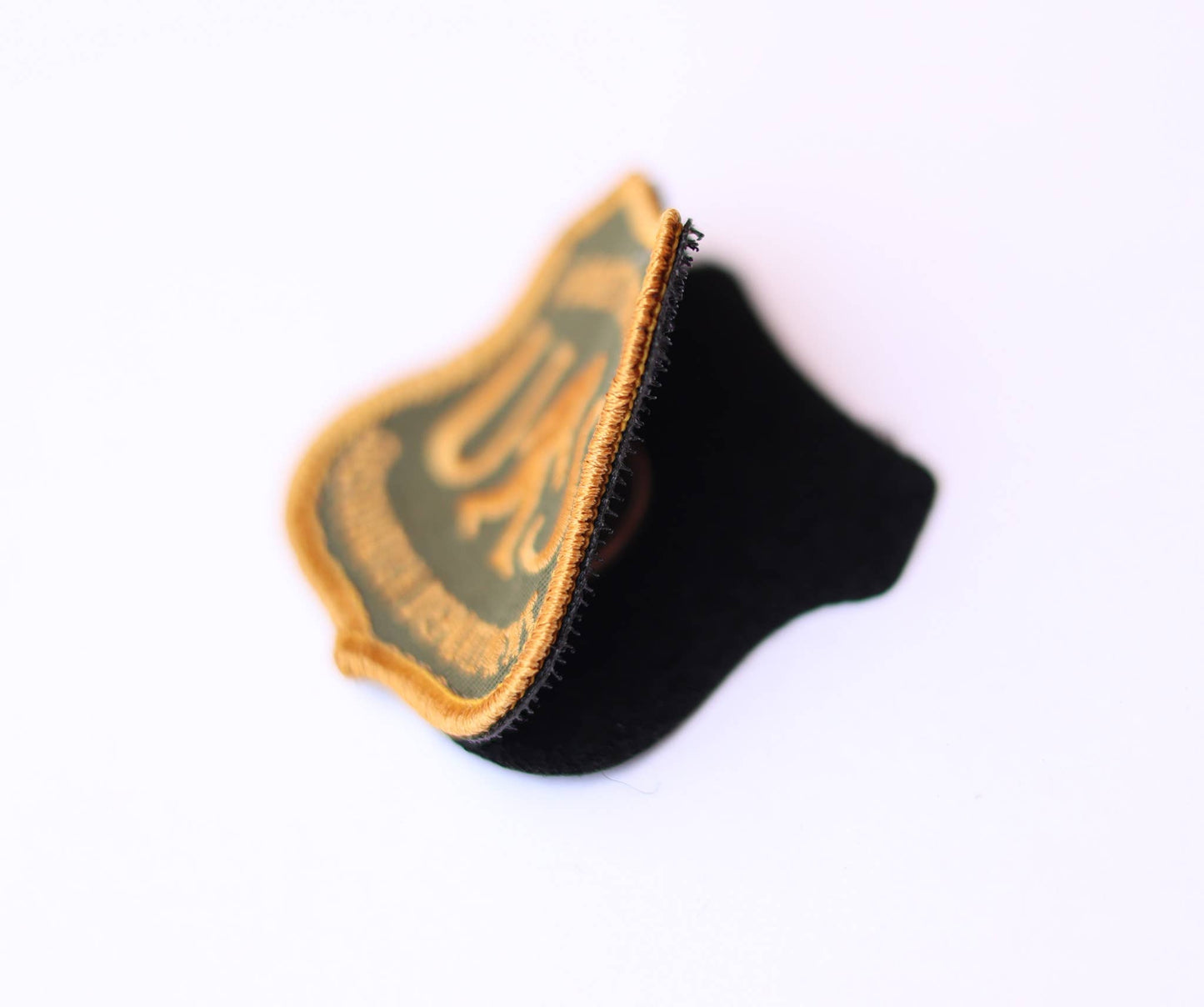 Tipped on edge, the US Sasquatch Department patch reveals its black backing and gold border stitch.