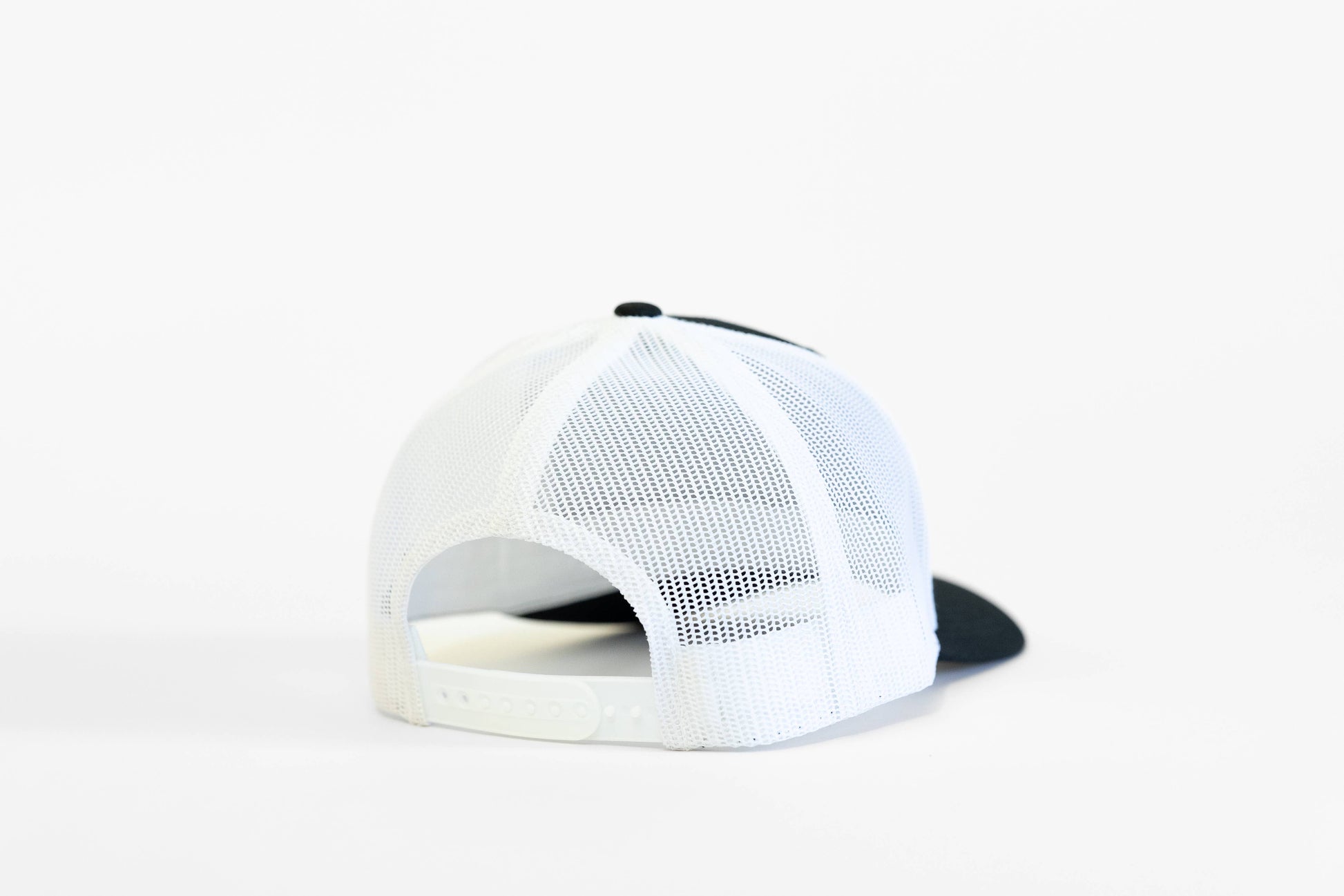 White mesh fills the rear of the black brimmed trucker hat, snap strap open at the center.