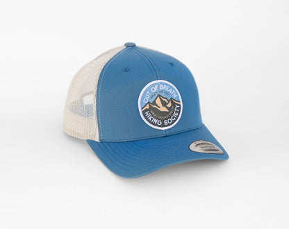 Steel blue front and stone mesh on the Out of Breath Hiking Society trucker hat, patch facing the camera.