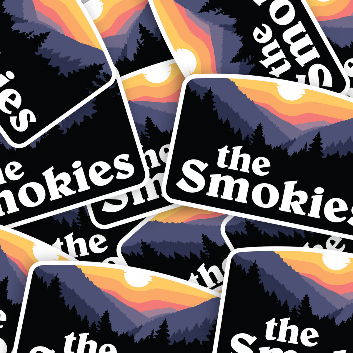 A scattered pile of The Smokies stickers overlaps edge to edge, repeating the sunset mountain design.