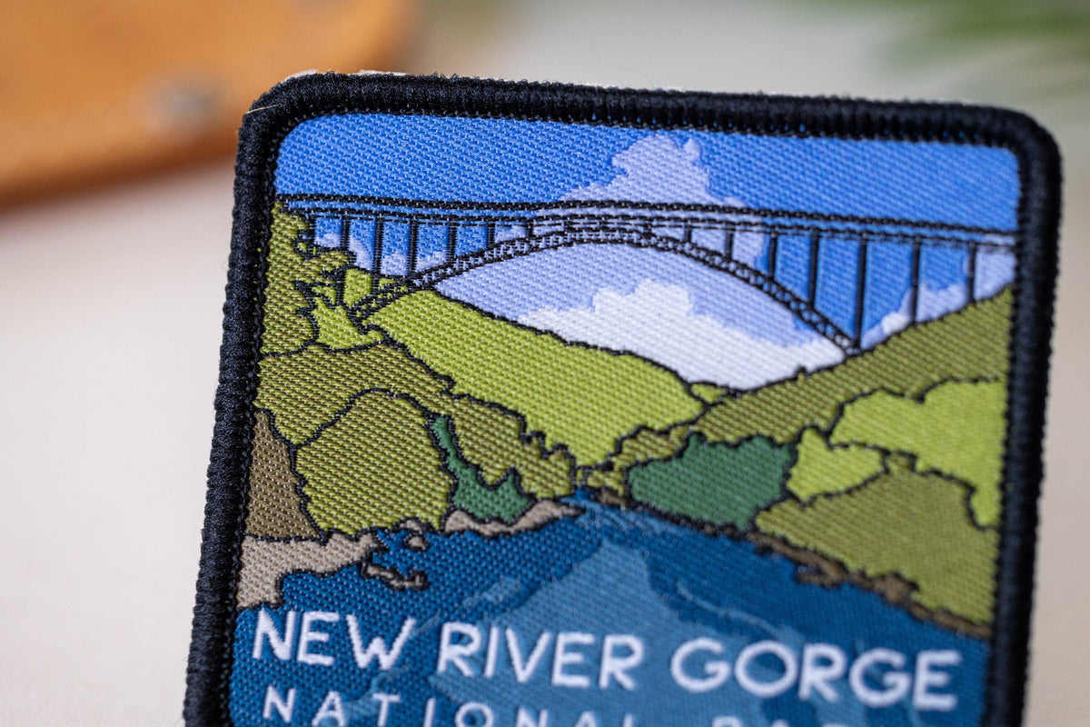 Close crop on the New River Gorge National Park patch, where black border stitching meets the bridge and blue sky.