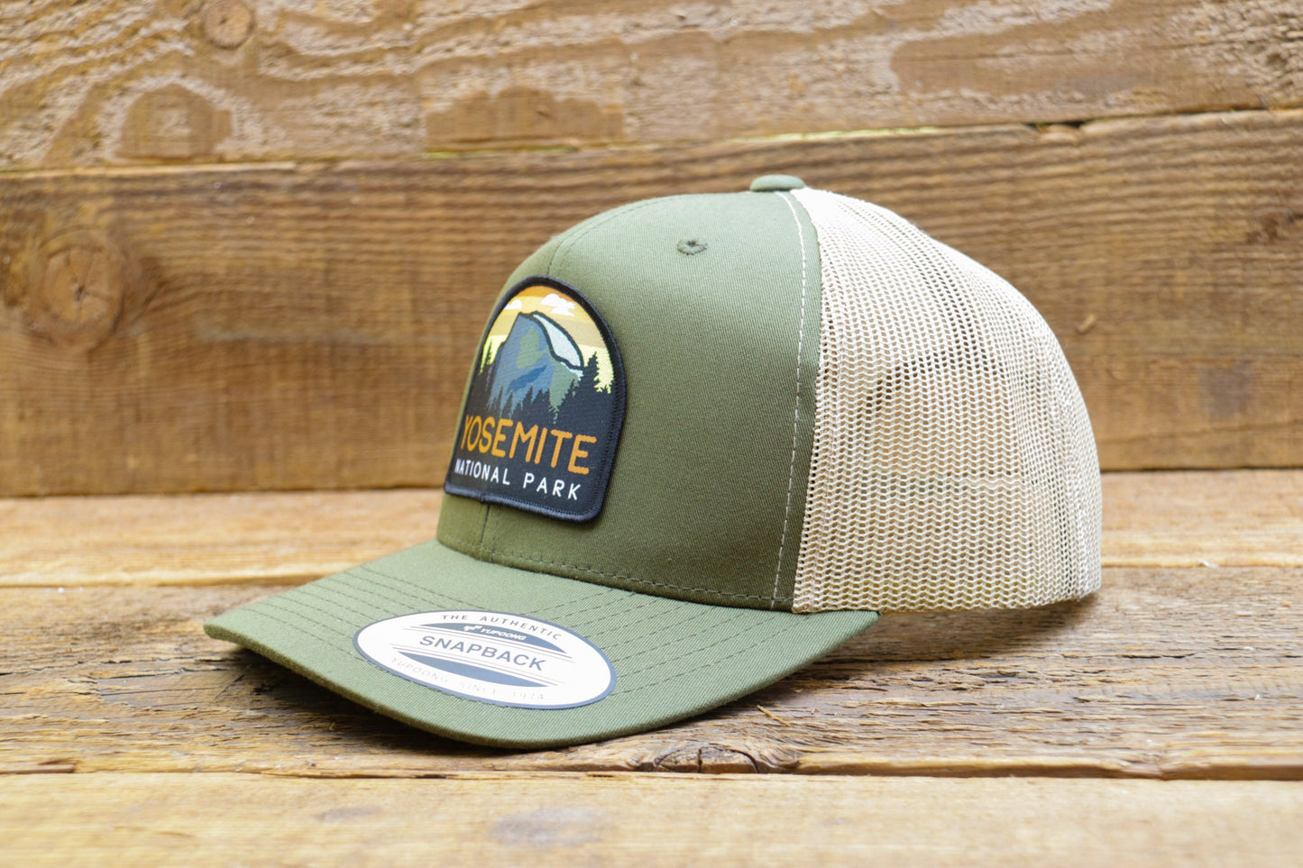 Resting on weathered barn wood, the green Yosemite National Park trucker hat still wears its snapback sticker.
