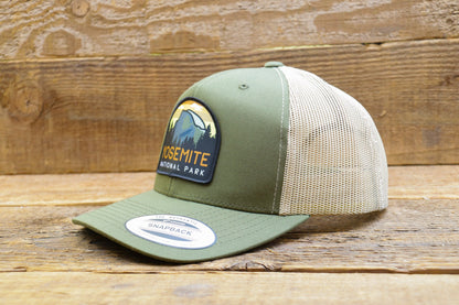 Resting on weathered barn wood, the green Yosemite National Park trucker hat still wears its snapback sticker.
