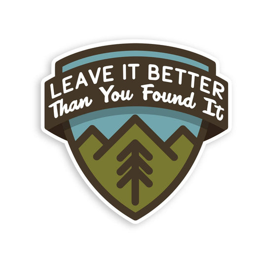 Shield shaped Leave It Better Than You Found It sticker with mountains and a pine tree on white.