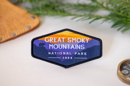 Resting on pale cloth near leather and a compass edge, the Great Smoky Mountains patch faces the camera.