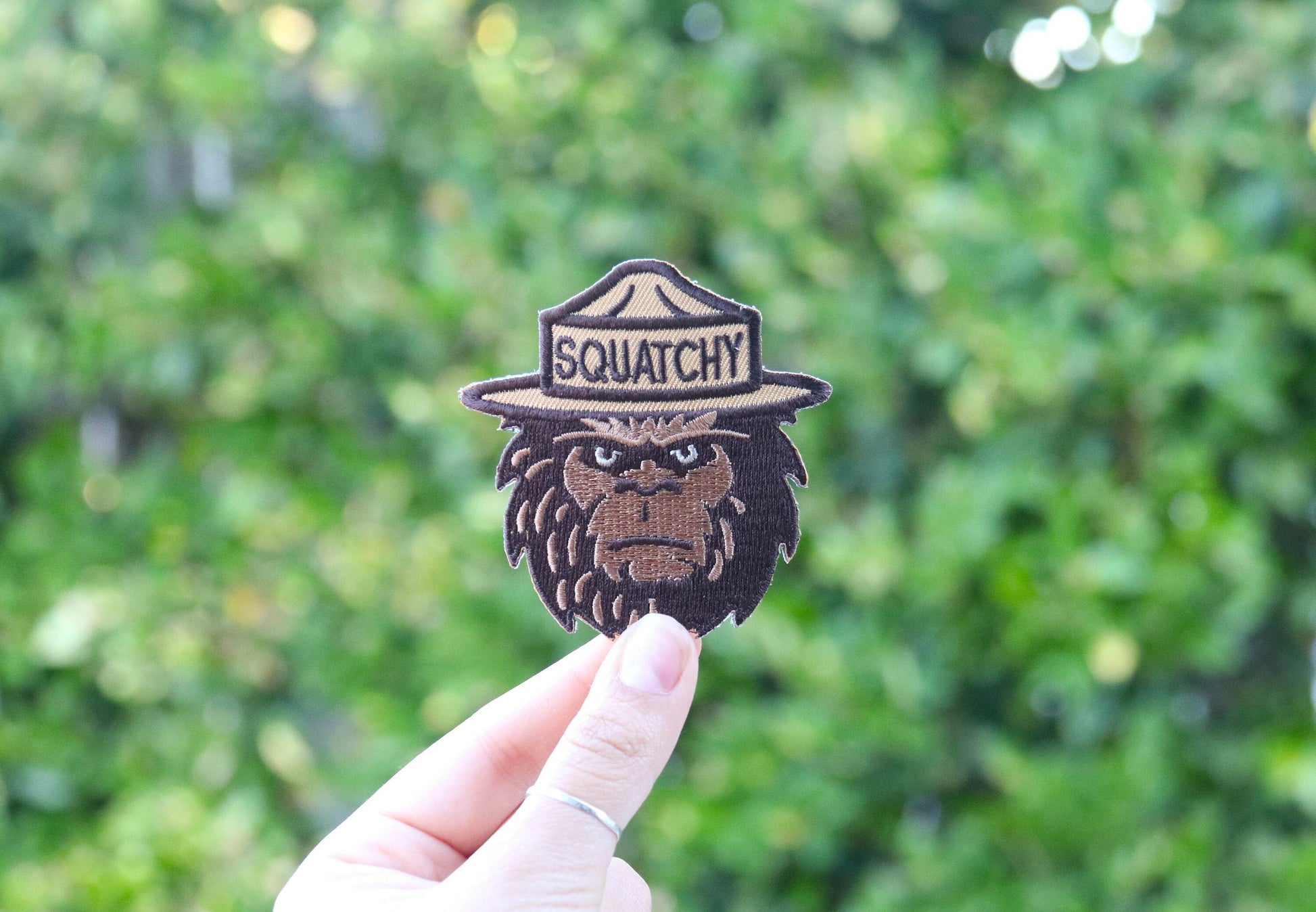 Held at arm's length in daylight, the Squatchy patch catches sun along its tan hat band.