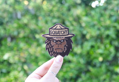 Held at arm's length in daylight, the Squatchy patch catches sun along its tan hat band.