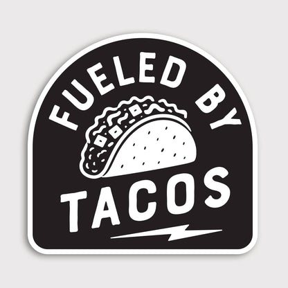 Black and white Fueled By Tacos sticker with an arched badge shape, taco drawing and lightning bolt below.