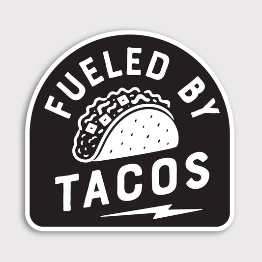 Black and white Fueled By Tacos sticker with an arched badge shape, taco drawing and lightning bolt below.